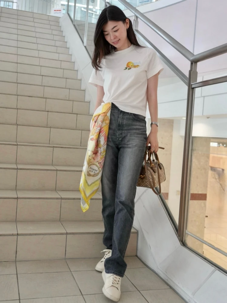H&Mの白Tシャツの裾にスカーフを片結びし、デニムと白スニーカーを合わせたカジュアルコーデ