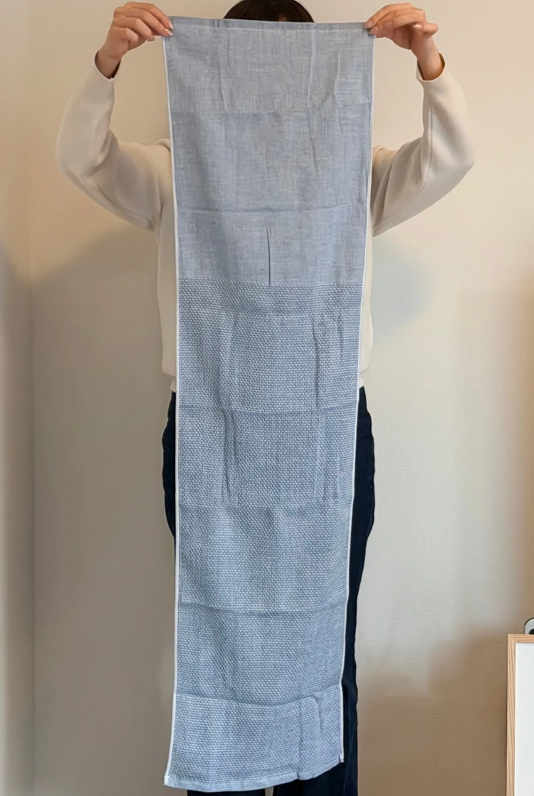 黄金湯オリジナル　ながい外気浴タオルを広げて持っている