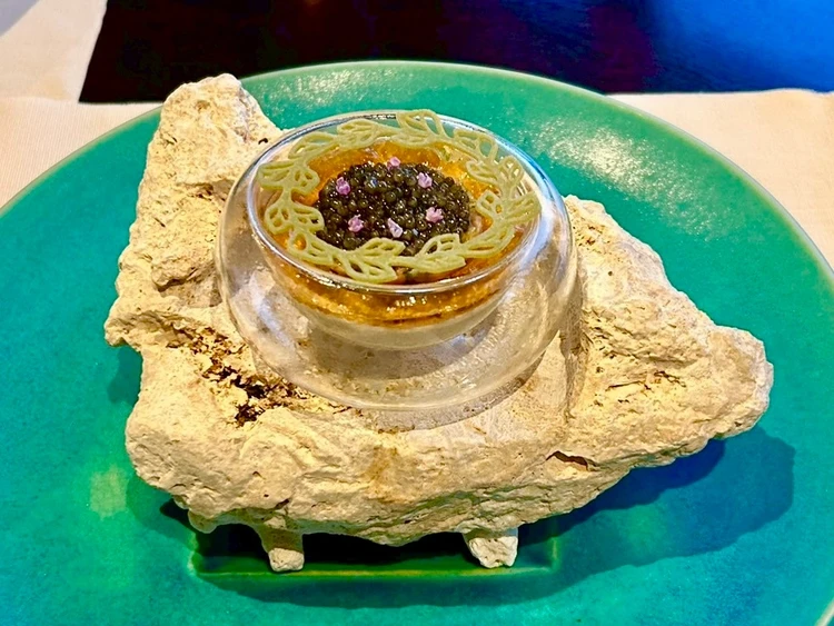 前菜のヤギとキャビアのタルタル フーチバの香り。青いお皿の上にガラスのボウルがある。