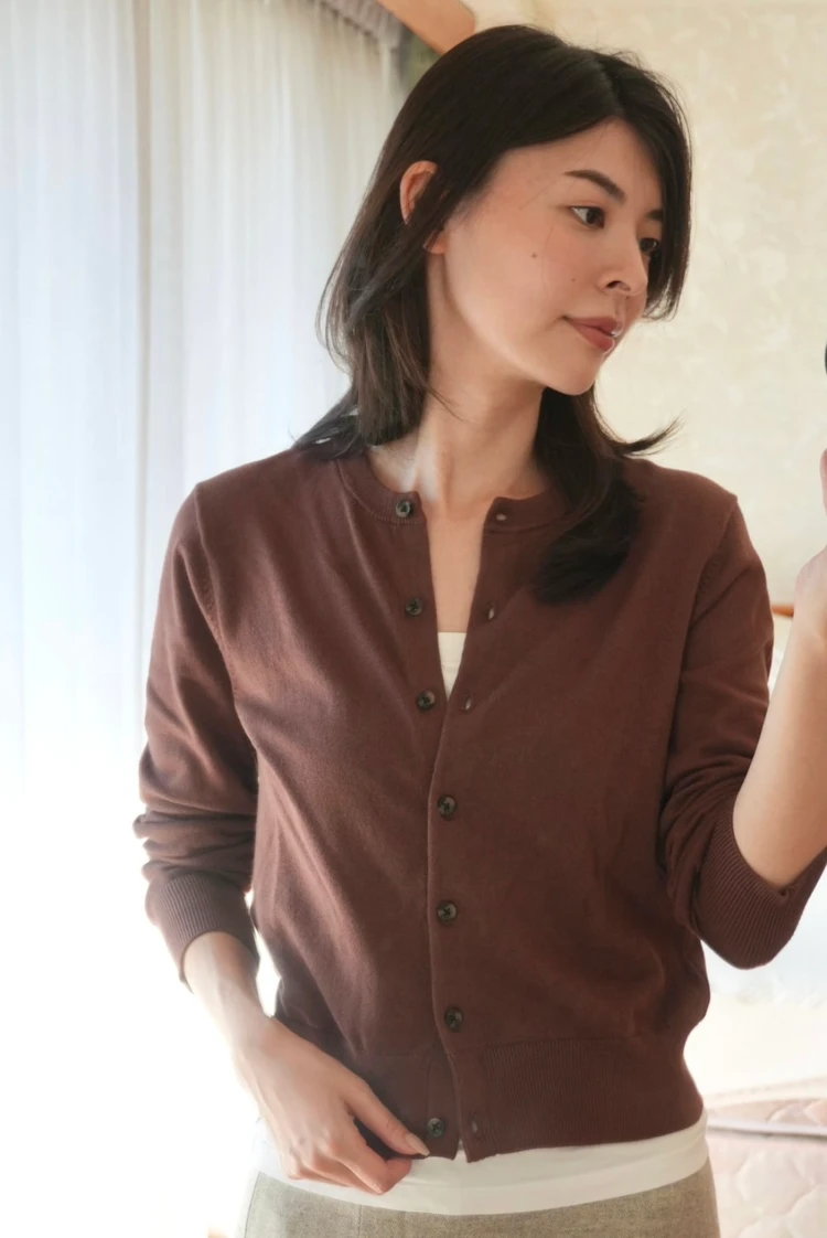 H&Mのブラウンカーディガンの裾から白いインナーをのぞかせた、スカートの重ね着スタイル