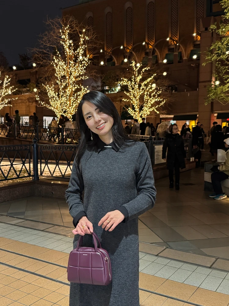 イルミネーション前で写真を撮る30代女性の写真