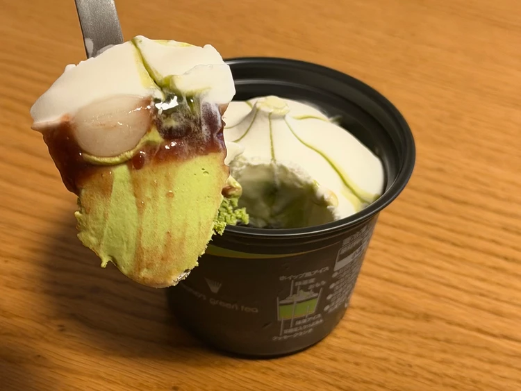 セブン‐イレブン限定「ナナズグリーンティー 抹茶パフェ」のアイス。スプーンで持ち上げた断面には、もちもちのおもち、濃厚な抹茶アイス、つぶあんが重なっている。
