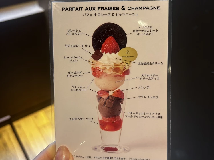 パフェ オ フレーズ ＆ シャンパーニュ」の構成解説。トップのビターチョコや中の生チョコ、シャンパーニュジュレ、弾けるキャンディー、一番下のショコラサブレまで、全層の素材がひと目でわかるメニュー図解。