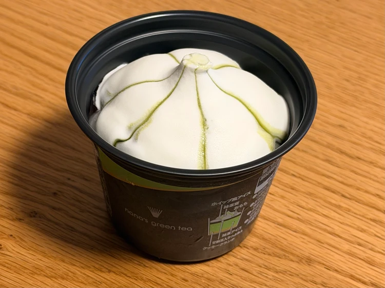 セブン‐イレブン限定「ナナズグリーンティー 抹茶パフェ」のアイスの蓋を開けたところ。ホイップ風の白いアイスクリームと緑色の抹茶蜜が見える。