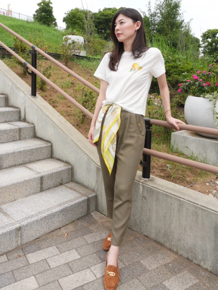 H&Mの白Tシャツの裾にイエロー系スカーフを片結びし、カーキパンツとローファーを合わせたコーデ