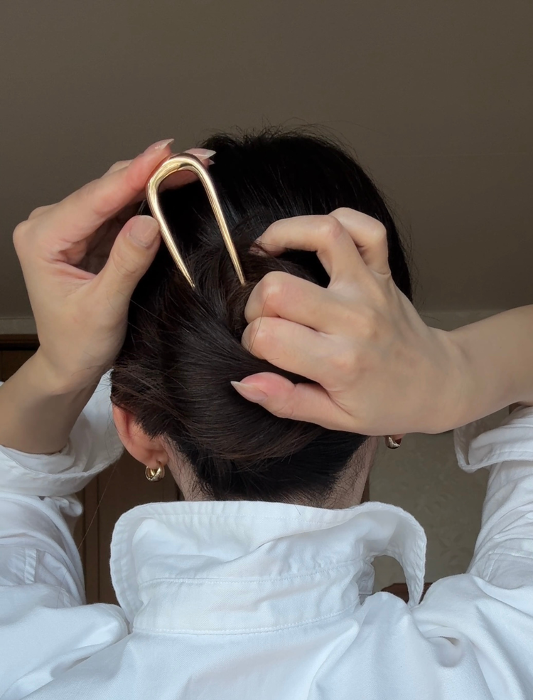Uピンを返して髪の根元にぐっと差し込んでいる様子