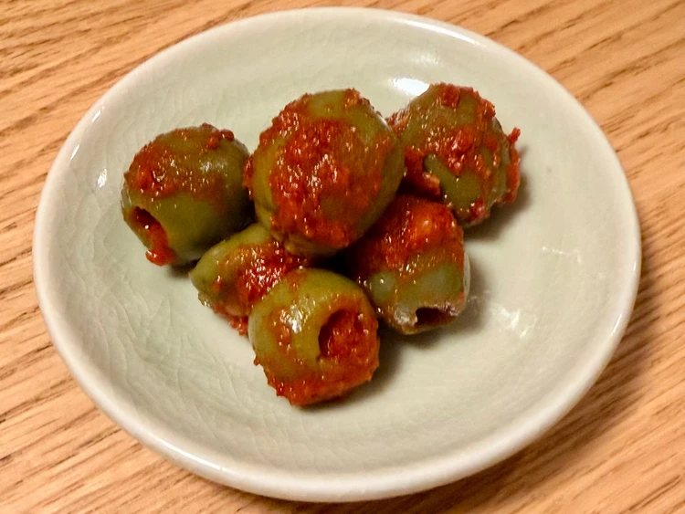 カルディで購入したハンマルの「オリーブキムチ」。白い小皿に盛られた緑色のオリーブと真っ赤なキムチダレ