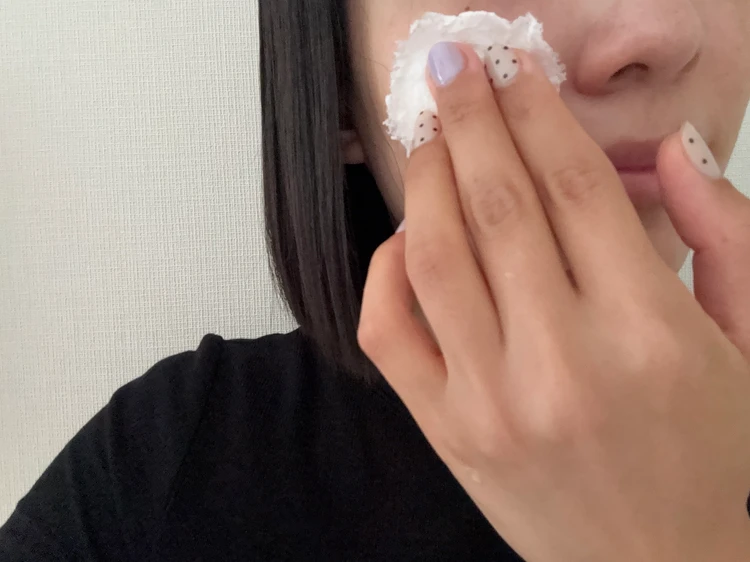 冷たいコットンを顔に当ててスキンケアする女性