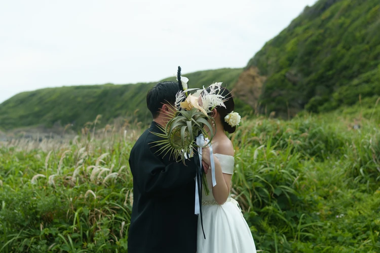 城ヶ島の草原でブーケ越しに顔を寄せる新郎新婦