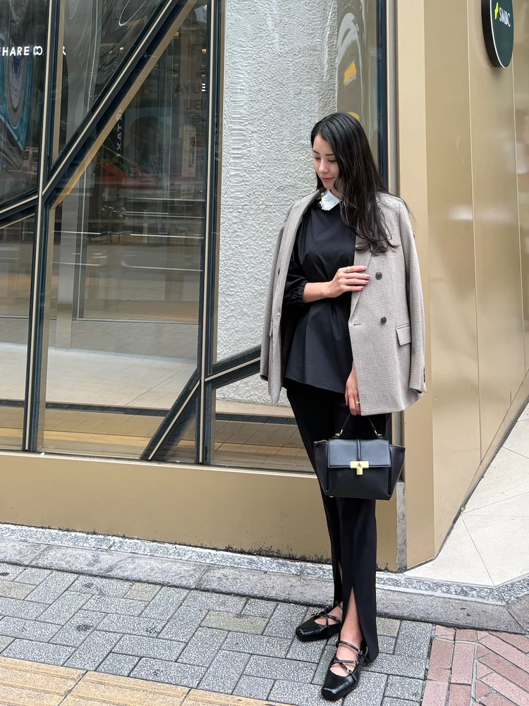 黒のコーデにチェック柄のジャケットを合わせてる写真