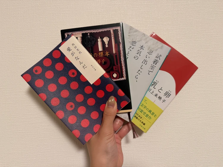 おすすめ小説『愛がなんだ』『薬指の標本』『試着室で思い出したら、本気の恋だと思う。』『乳と卵』の4冊を手に持った写真