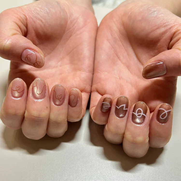 甘さ控えめで楽しむ大人世代のバレンタインネイルデザイン ブラウンとピンクのマグネットネイルにLOVEの繋げ文字とハートアートを取り入れたデザイン 冬ネイル