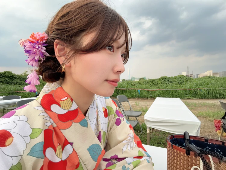 生成り地の華やかな花柄浴衣を着た女性の横顔。低めにまとめたヘアアレンジに、浴衣の柄色を拾ったパープル系の花飾りを合わせている