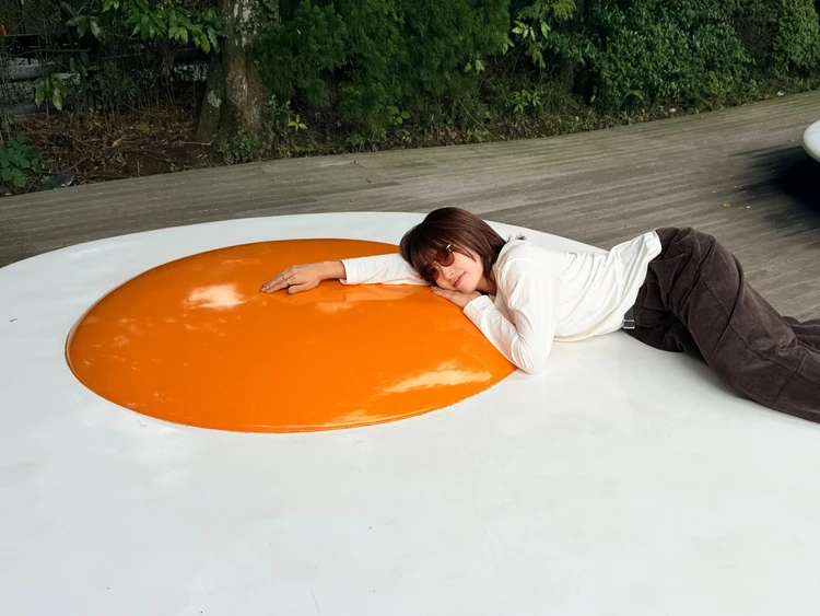 箱根彫刻の森美術館の目玉焼き型ベンチに寝そべって、ぐでたま風にポーズする様子