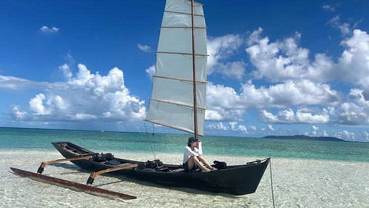 幻の浜に浮かぶサバニ。白い砂浜とエメラルドグリーンの海。