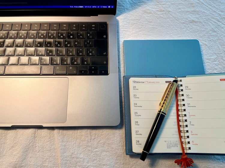 パソコンの横にWATERMANの万年筆とノートを置いている様子