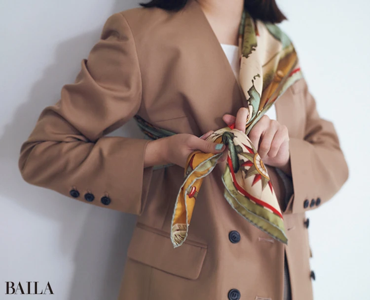 1と同じく三角に折ったスカーフを片方の肩をおおうようにかけ、両端をわきの下で結ぶ。ジャケットのボタンは開け、抜け感を出すのも忘れずに。