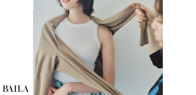 《1》カーディガンはボタンを留めず、フロントが内側になるよう持ったら、中心からズレるようにどちらか片方の肩にかぶせる