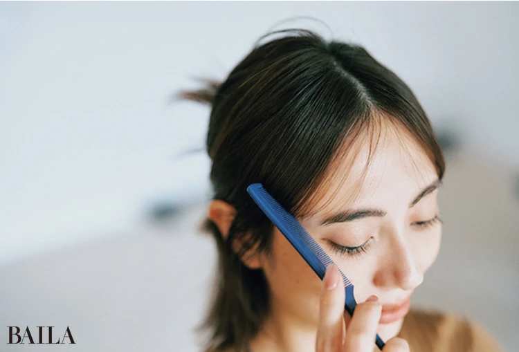 《2》スプレーをかけたコームで前髪をおさえるようにして整える。このひと手間でくずれにくさとツヤ感が格段にアップ