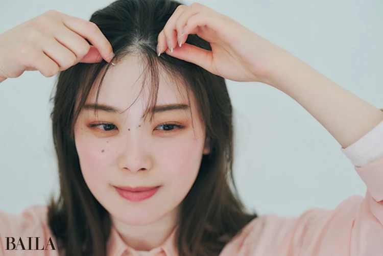 《2》オールバックにした前髪から、親指と人さし指を使って毛束を2～3つ引き出し、透けバングをつくる。