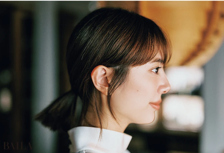 《2》耳下の位置でひとつ結びを。耳前と耳後ろ、それぞれに後れ毛を出し、同じくヘアミルクを適量つけて整える。