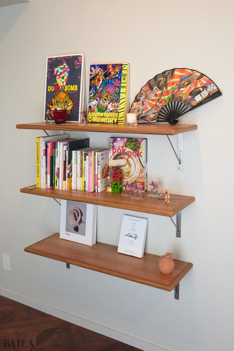 中古マンション。ダイニングの壁に棚を造作。料理本やフィギュアなど、目に入ると気分が上がるアイテムが並ぶ。