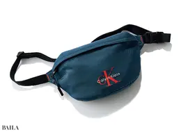 シックなネイビー基調のボディに、パキッと明るいオレンジのロゴがよく映える。水や汚れに強い ナイロン素材。（14×24×6.5）￥16500／カルバン・クライン カスタマーサービス（カルバン・クライン）