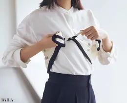 スカーフを対角線で三角に折り、両端を持って胸のあたりで結ぶ。前から見たときに三角の頂点が片足にかかるくらいまで、結び目を後ろにずらす。