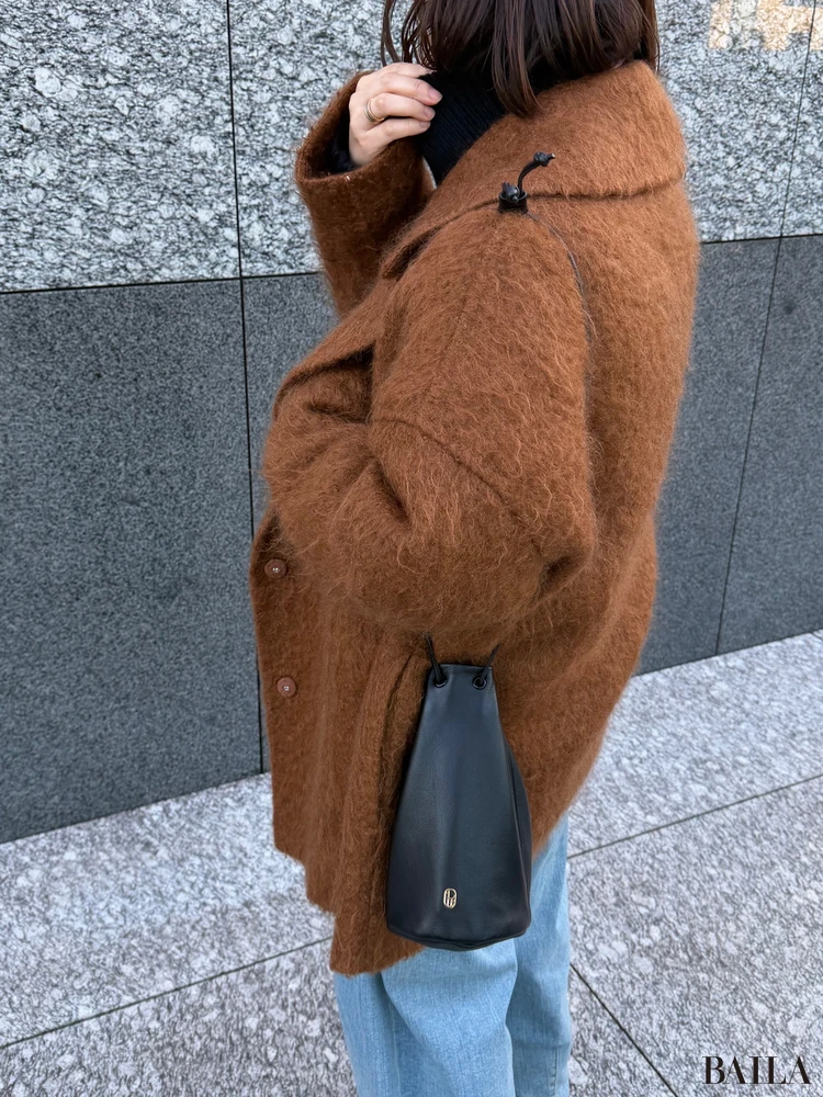 (im)perf.(インパーフ)の黒ポーチを肩から下げているところ(寄り)。