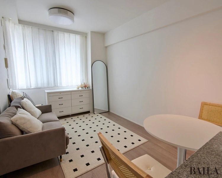 白で統一したスッキリとしたリビングルーム。できるだけモノを収納し、開放感のある空間に。大きな窓から差し込む陽の光のおかげで、日中は照明をつけなくても過ごせる。