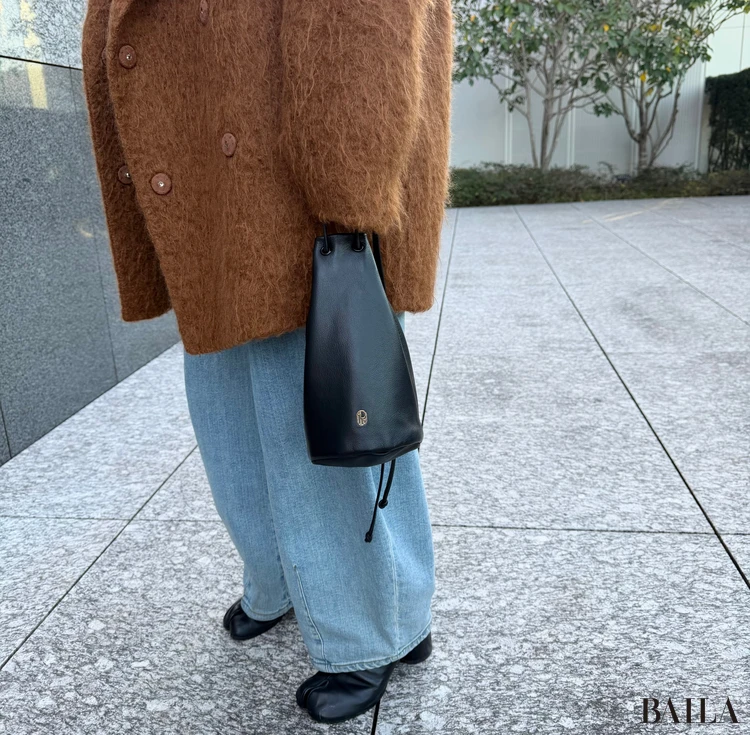 (im)perf.(インパーフ)の黒ポーチを指持ちしているところ(寄り)。