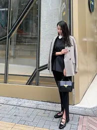 黒のコーデにチェック柄のジャケットを合わせてる写真